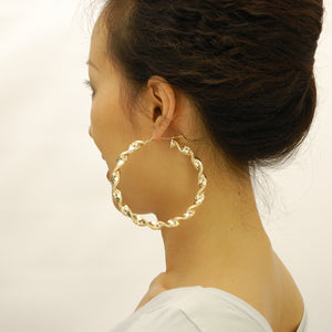 Model wearing large 3-inch 10k yellow gold 8mm twisted hoop earrings