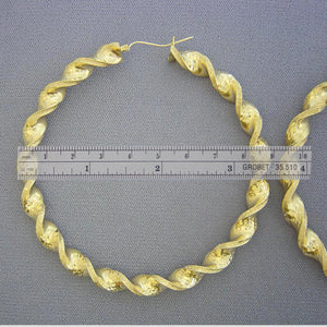 Close-up of 8mm thick 10K yellow gold twisted hoop earring with secure clip closure