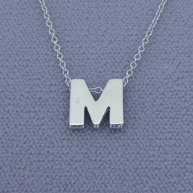 Solid gold 3D double plate diamond initial pendant styled flat on gray background