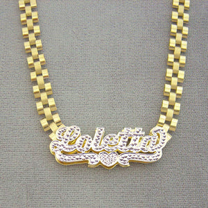 Custom 10K yellow gold iced out nameplate laying flat on 6mm watch-band style chain