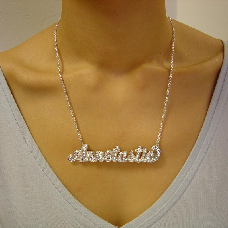 Model wearing a large custom 3D sterling silver cursive nameplate necklace attached to a silver rolo chain.
