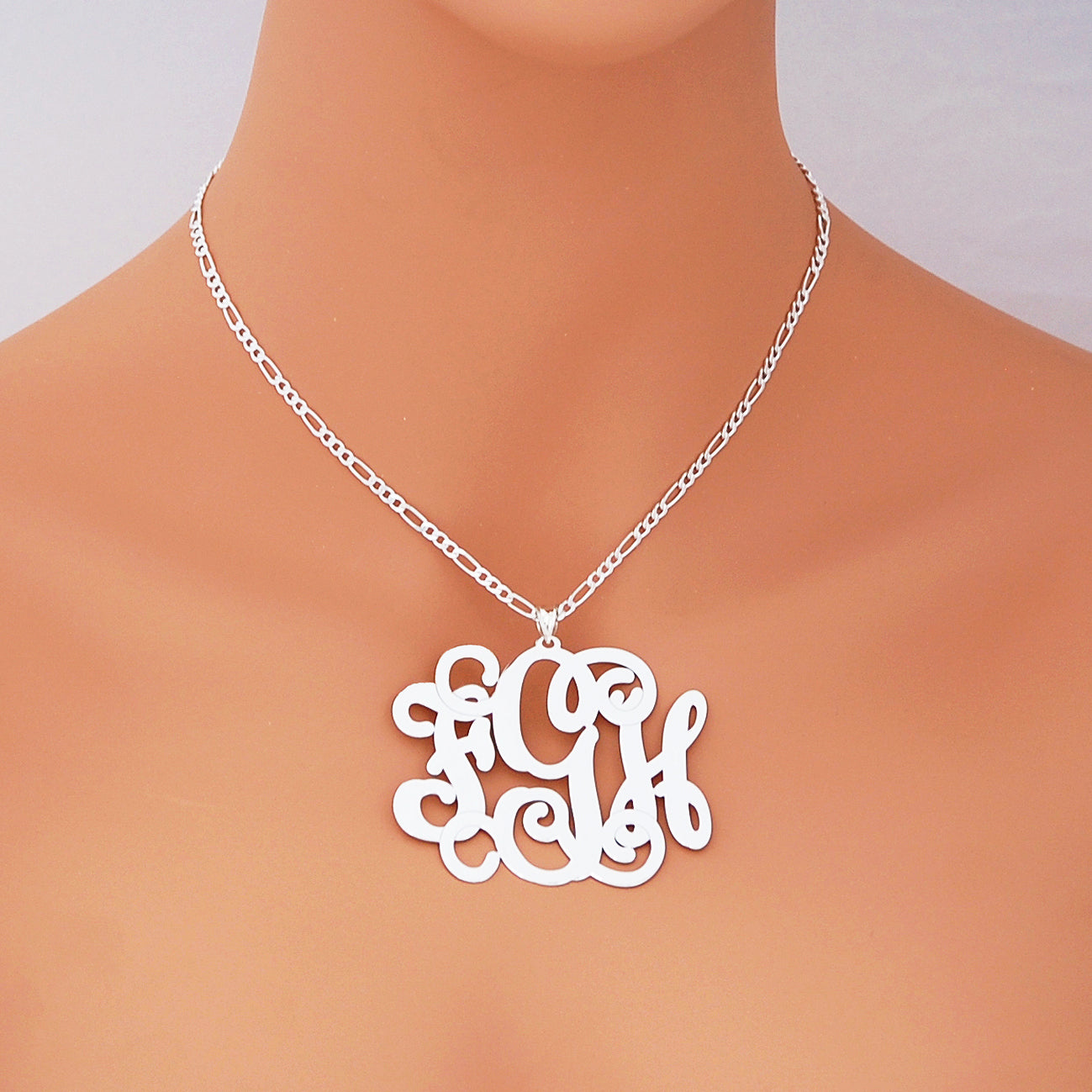 Model wearing a custom 2.5-inch 925 sterling silver monogram pendant necklace against a light orange background.