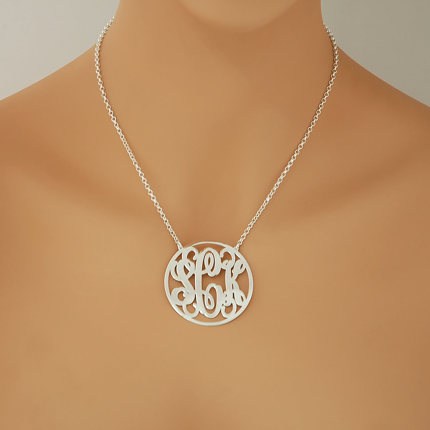 Woman wearing a personalized sterling silver 3-initial circle monogram necklace attached to a silver rolo chain.