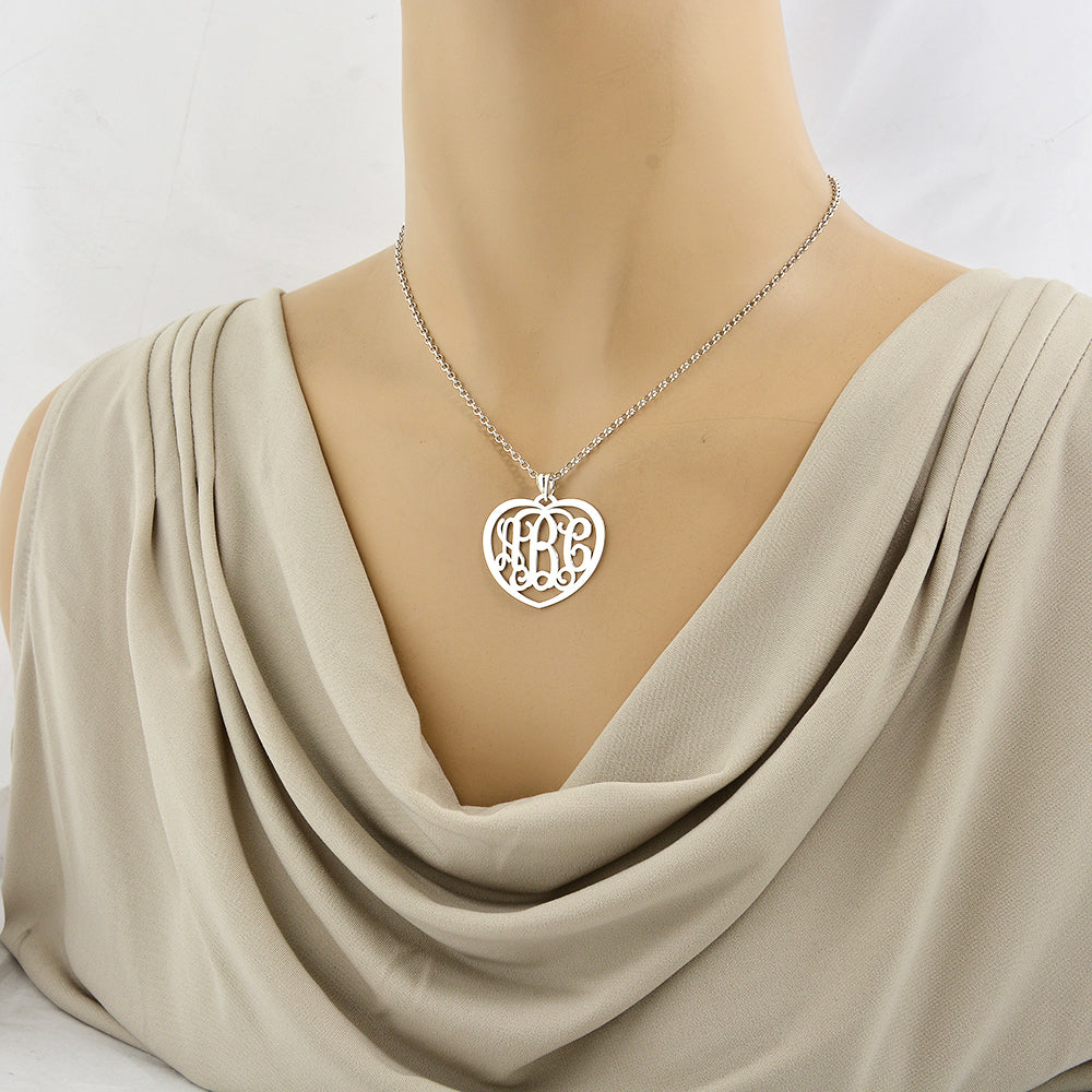 Model wearing a personalized sterling silver heart monogram pendant necklace over a neutral beige top.