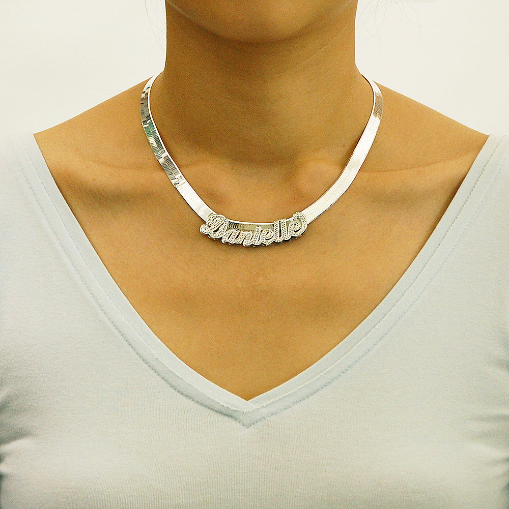 Model wearing a personalized sterling silver 3D script name necklace with an 8mm herringbone chain around the neck.