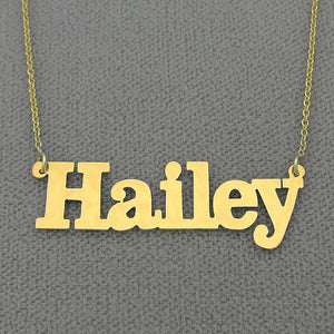 Close-up view of a custom laser-cut solid gold block font name pendant showing precise edges and polished finish.