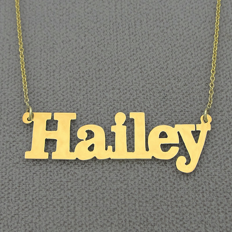 Close-up view of a custom laser-cut solid gold block font name pendant showing precise edges and polished finish.
