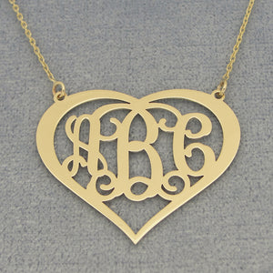 Close-up of a custom 14k gold heart monogram pendant with three personalized initials.