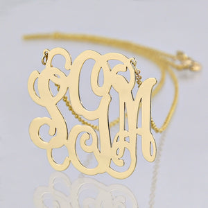 Close-up of a custom solid gold 3 initial monogram necklace.