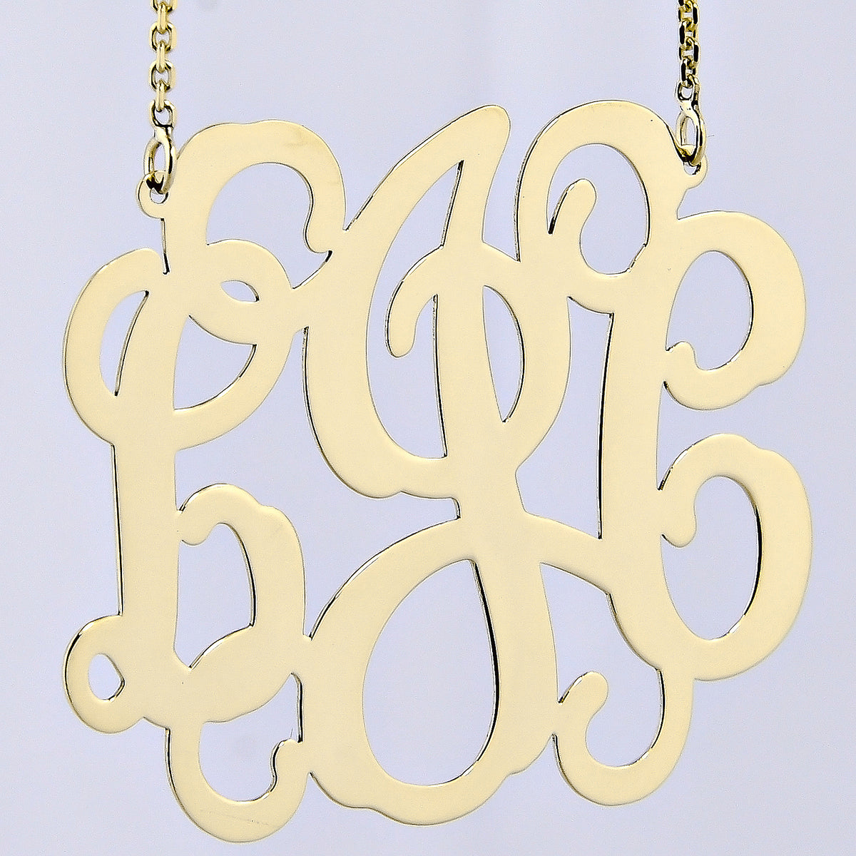Solid gold custom three-initial monogram necklace worn as a pendant