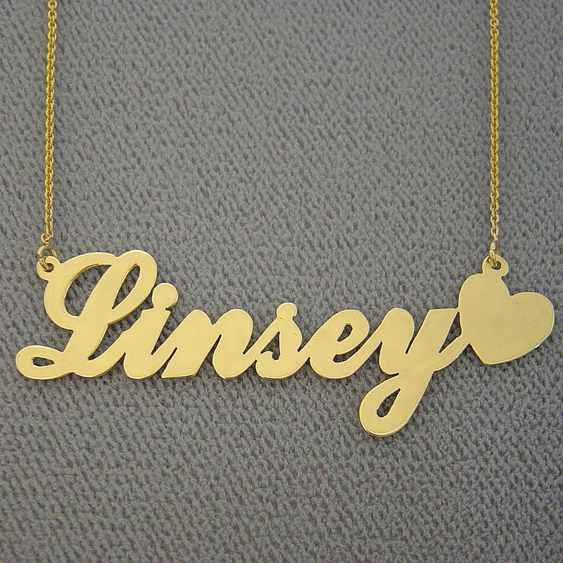 Close-up detail of a laser-cut gold custom name pendant with a solid heart end on a dark background.