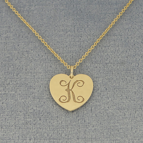 Custom laser engraved cursive letter K monogram on a solid gold heart disc pendant