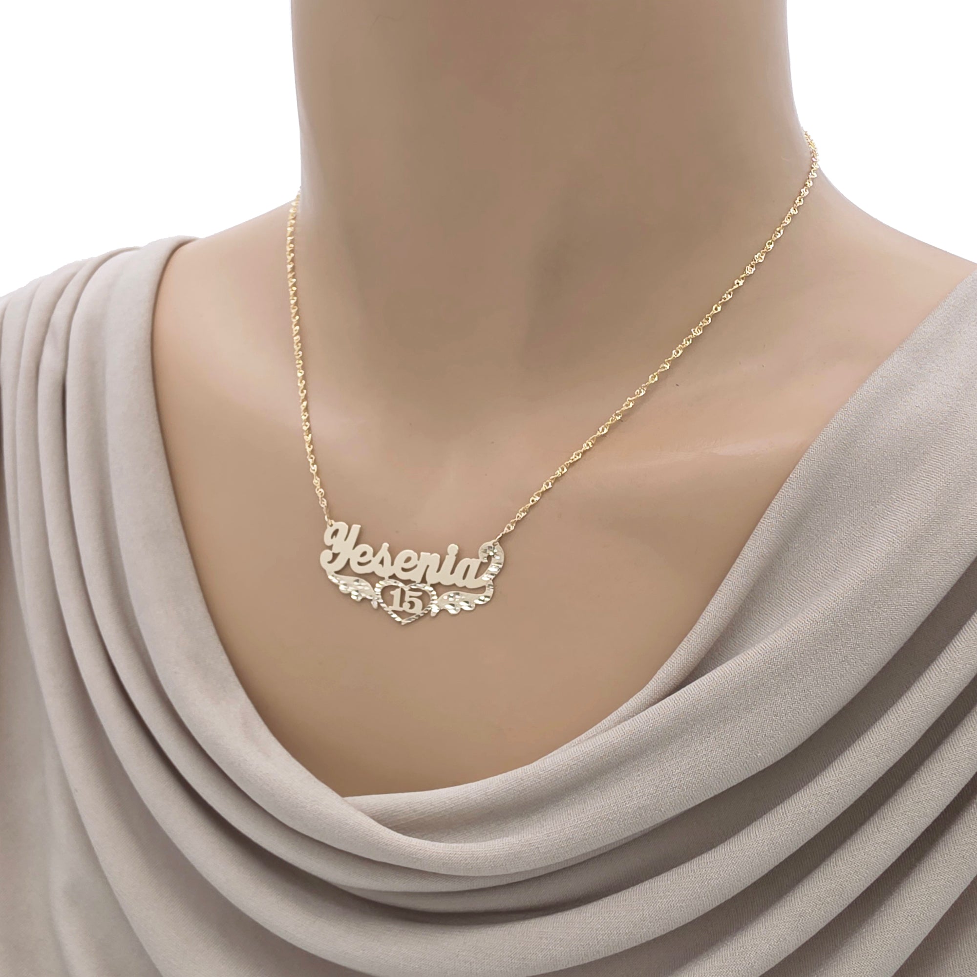 Model wearing the custom 10K/14K gold Sweet 16 name necklace with wings and heart pendant.