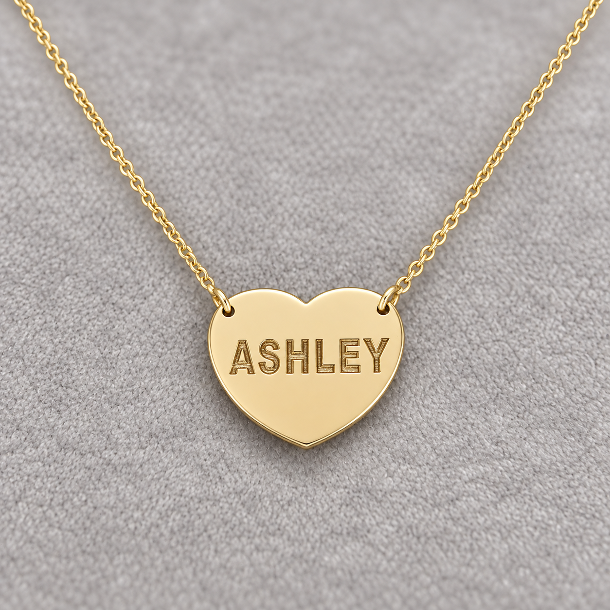 Close-up of a solid gold heart necklace with ASHLEY laser engraving