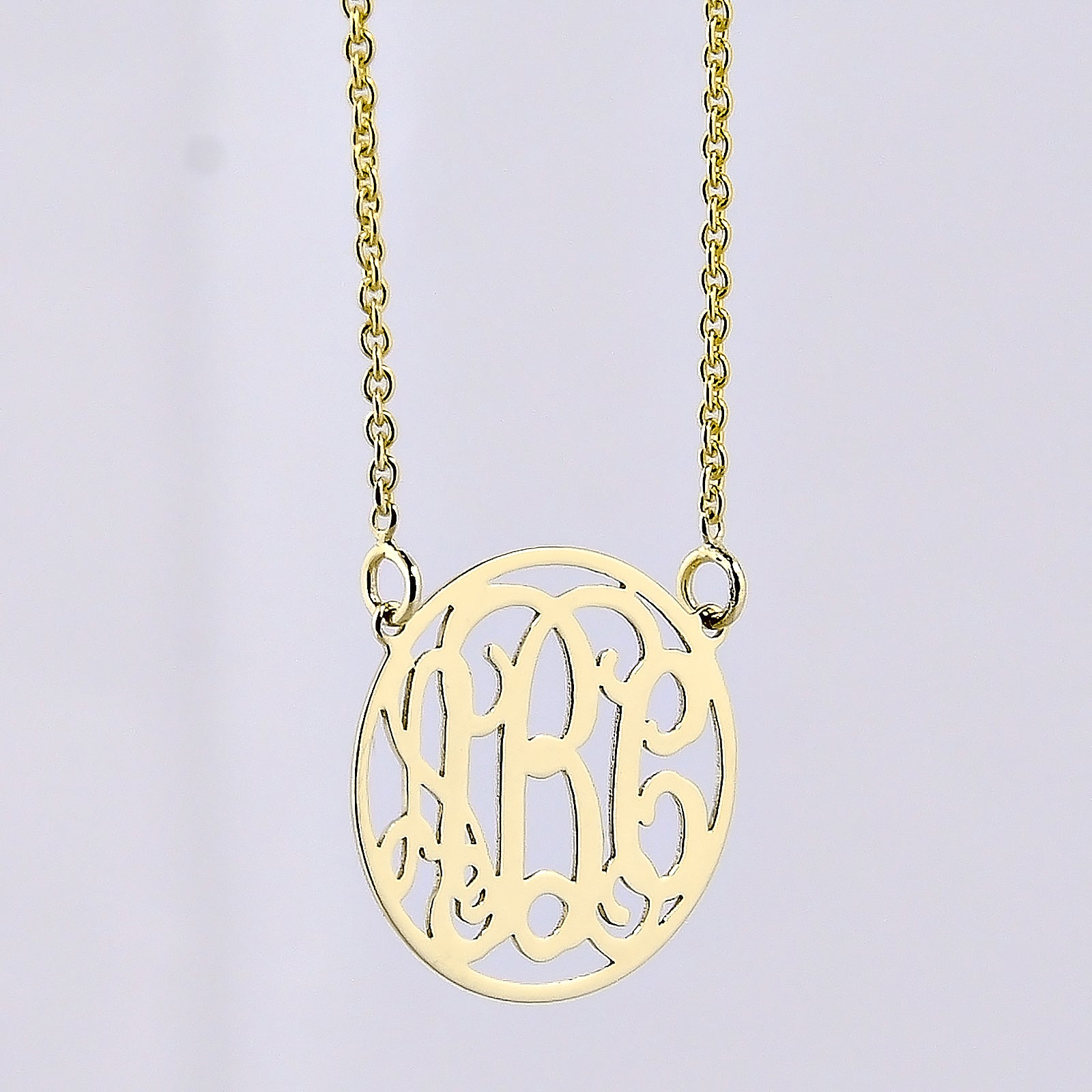 Close-up of an extra small 1/2-inch solid gold circle monogram necklace with a three-initial pendant.