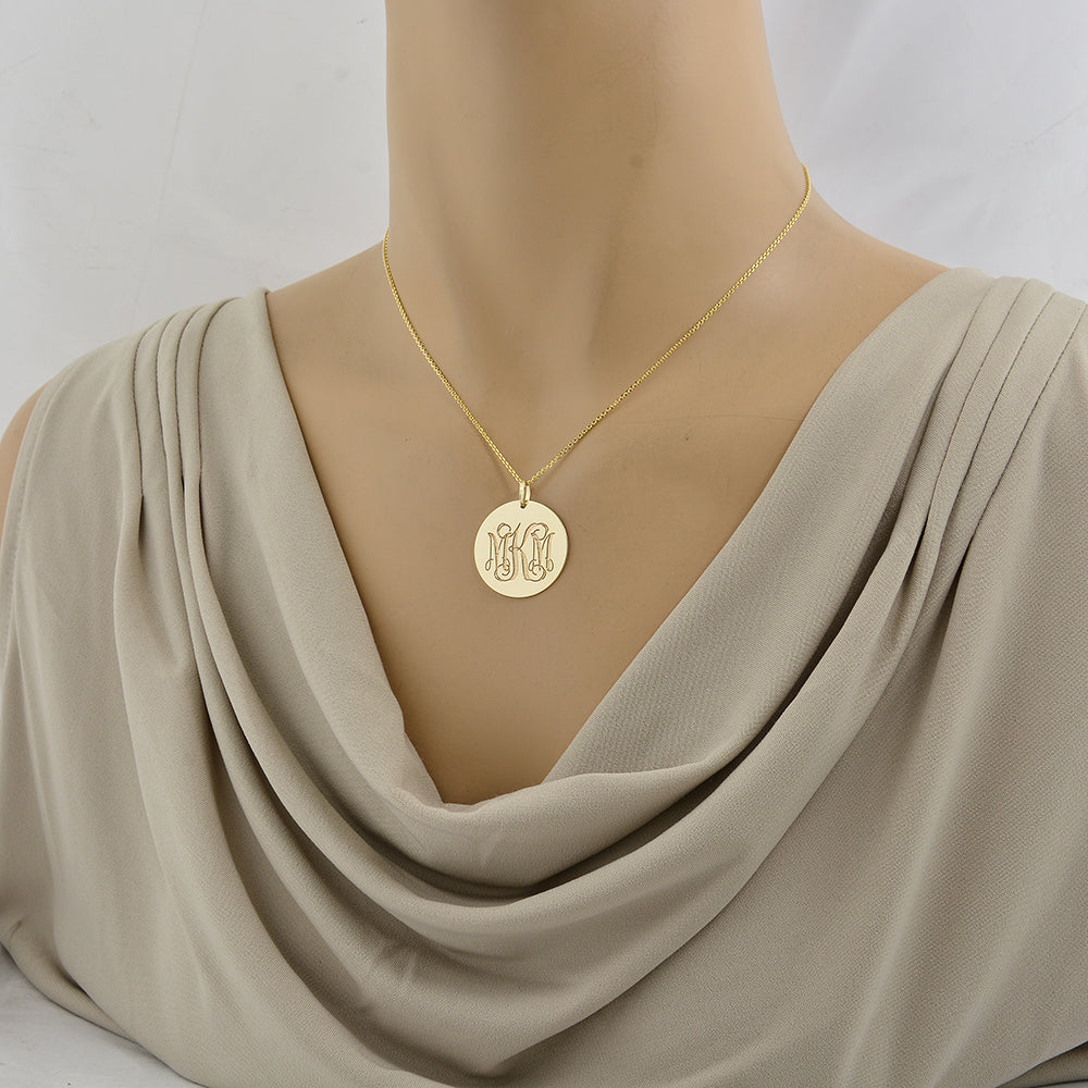 Layered solid gold monogram disc pendant necklace shown on a display mannequin