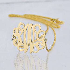 Close-up of a laser-cut 14K solid gold three-initial monogram pendant necklace.