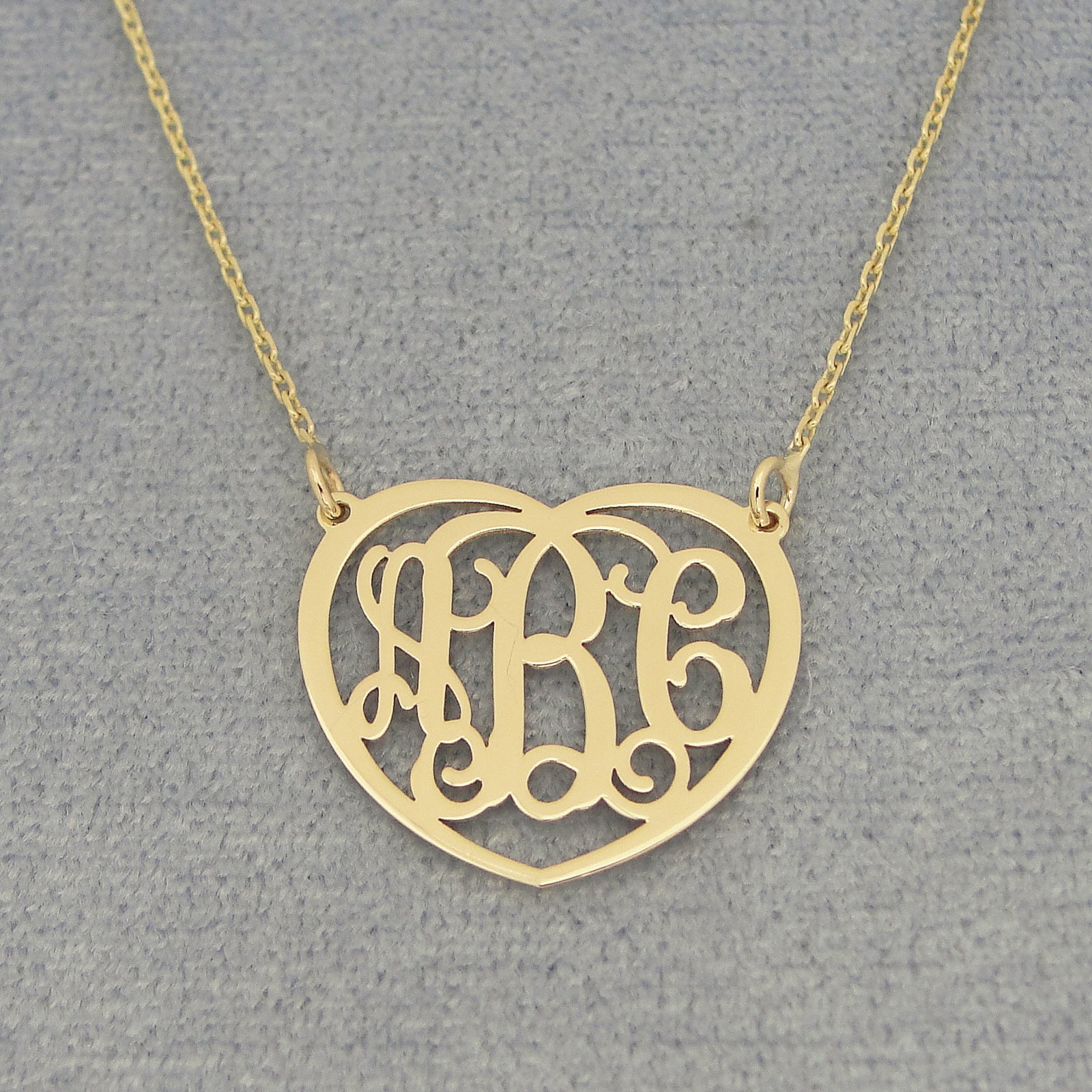 Close-up of laser-cut solid gold 3-initial heart monogram pendant