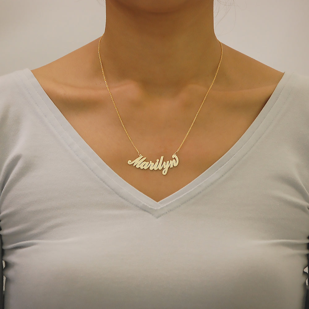 Woman wearing a custom curved cursive solid gold nameplate necklace crafted in 14k gold.