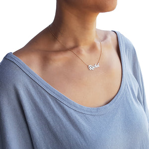 Woman wearing a small solid gold custom script name necklace on a 16-inch chain.