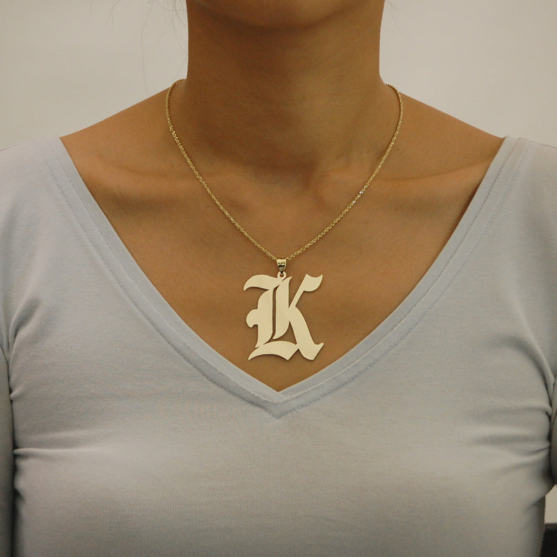 Model wearing solid gold Gothic initial pendant charm on a gold rope chain