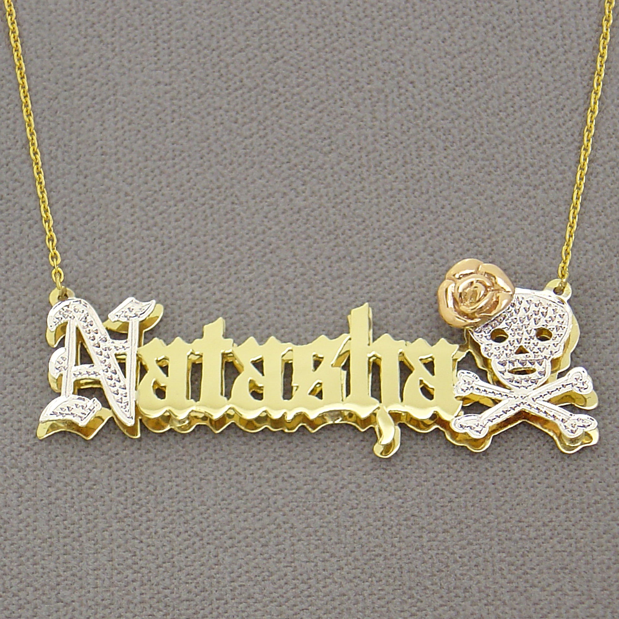 Close-up detail of the custom nameplate pendant showing diamond-cut rhodium accents on the skull and Old English lettering.