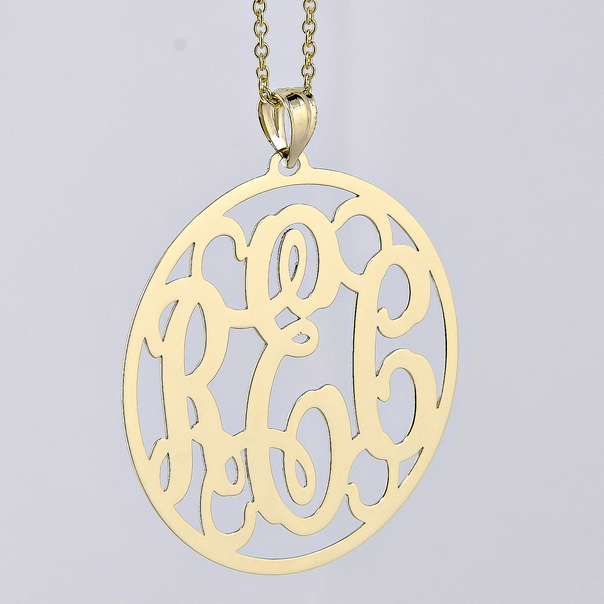 Close-up detail showing the thickness and polished finish of a custom solid gold circle monogram pendant