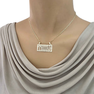 Close-up view of a custom gold rectangular name pendant styled on a mannequin chain.
