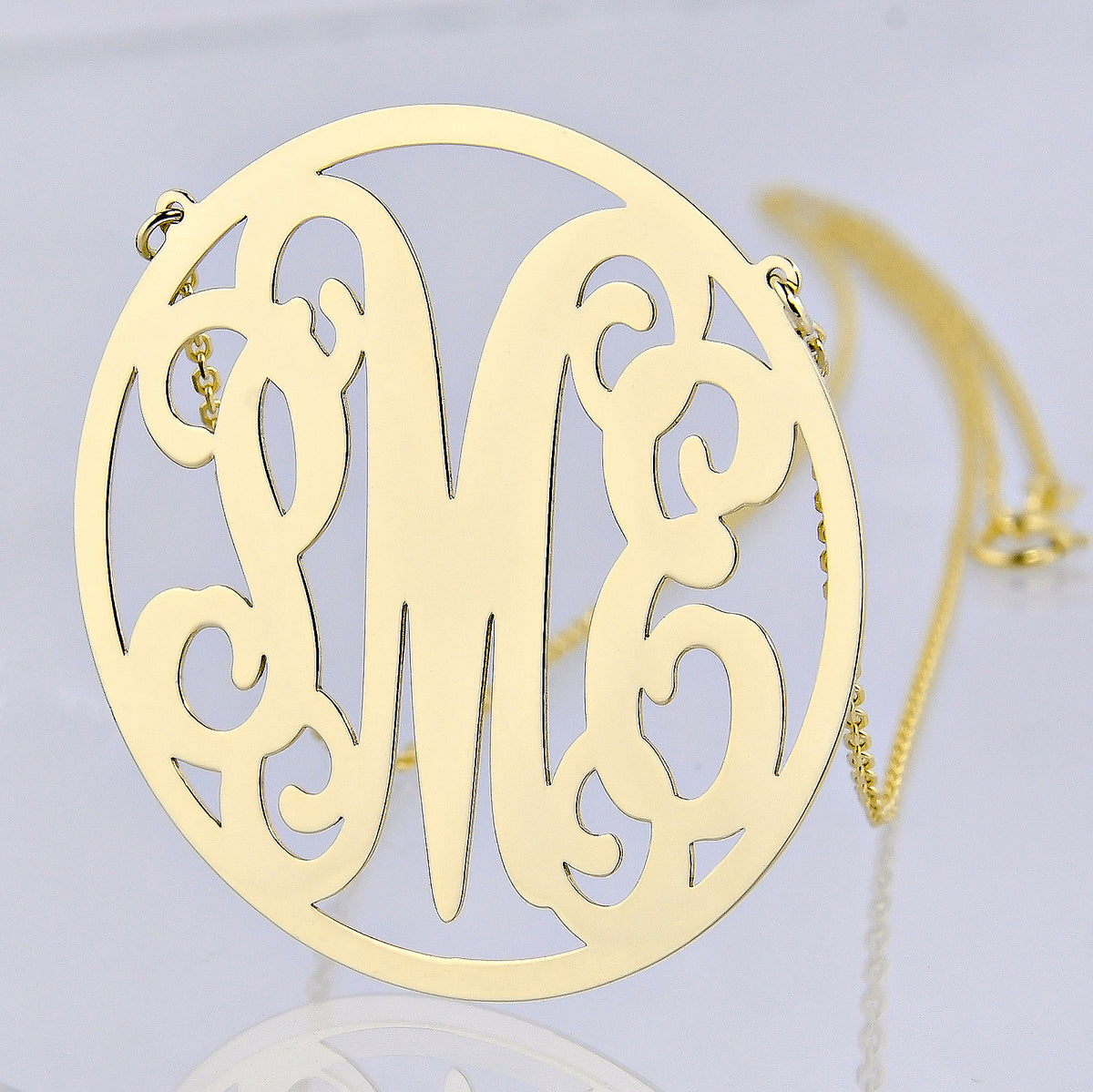 Personalized solid gold circle monogram necklace with three custom initials.