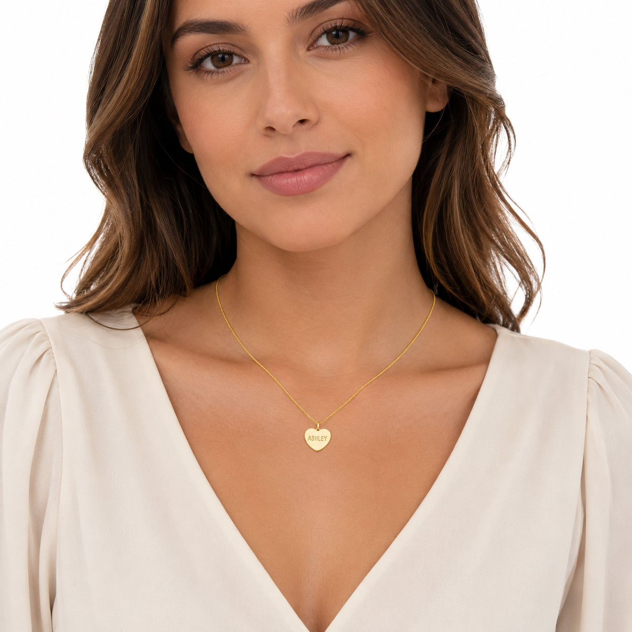 Model wearing a personalized yellow gold heart disc pendant necklace engraved ASHLEY