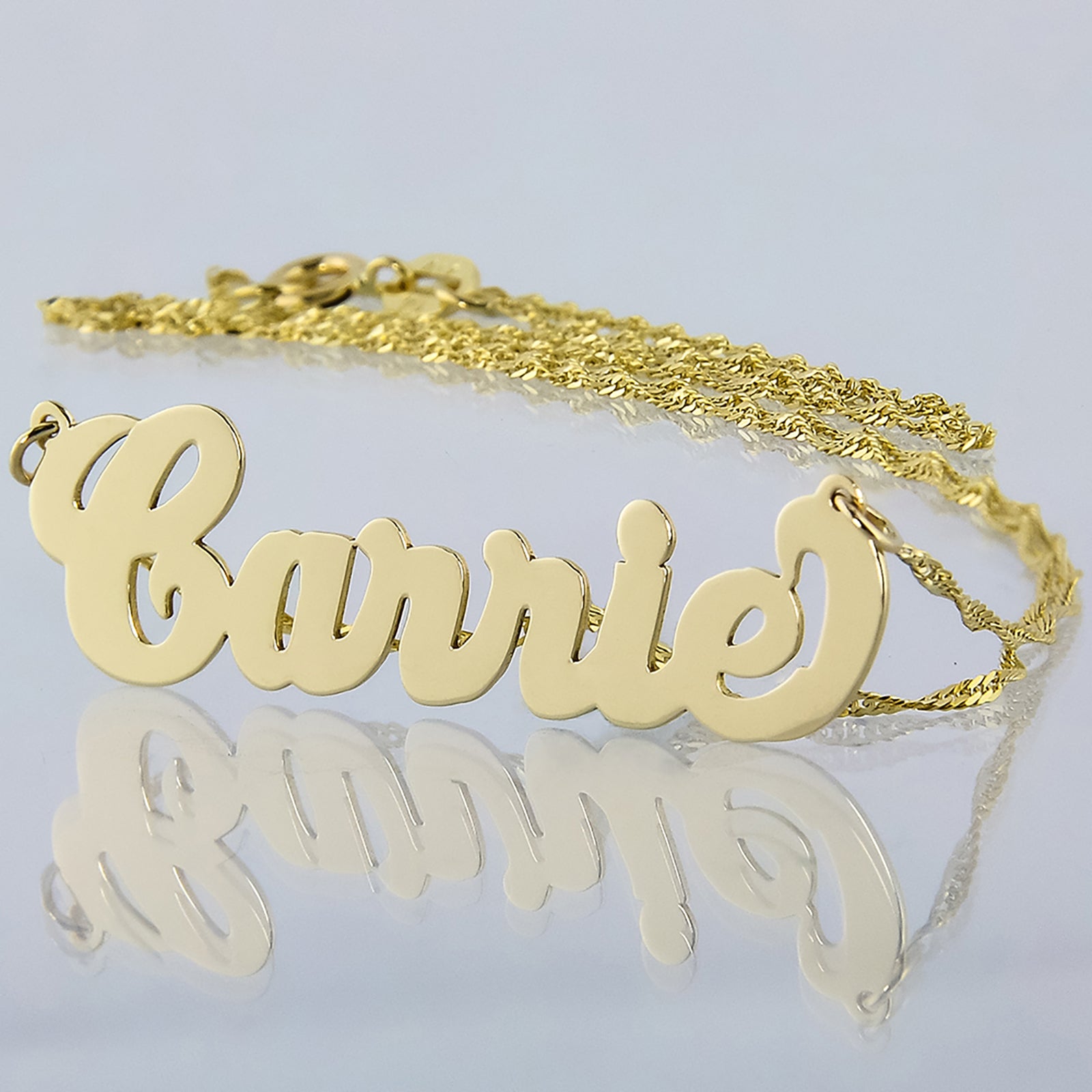 Small 10k yellow gold cursive Carrie script name necklace on a white background