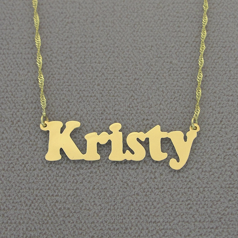 A small solid gold name necklace featuring the name "Kristy" in block letters, hanging from a delicate yellow gold chain.