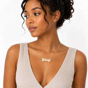 A woman wearing a delicate gold nameplate necklace that reads 'Johnny' on a white background.