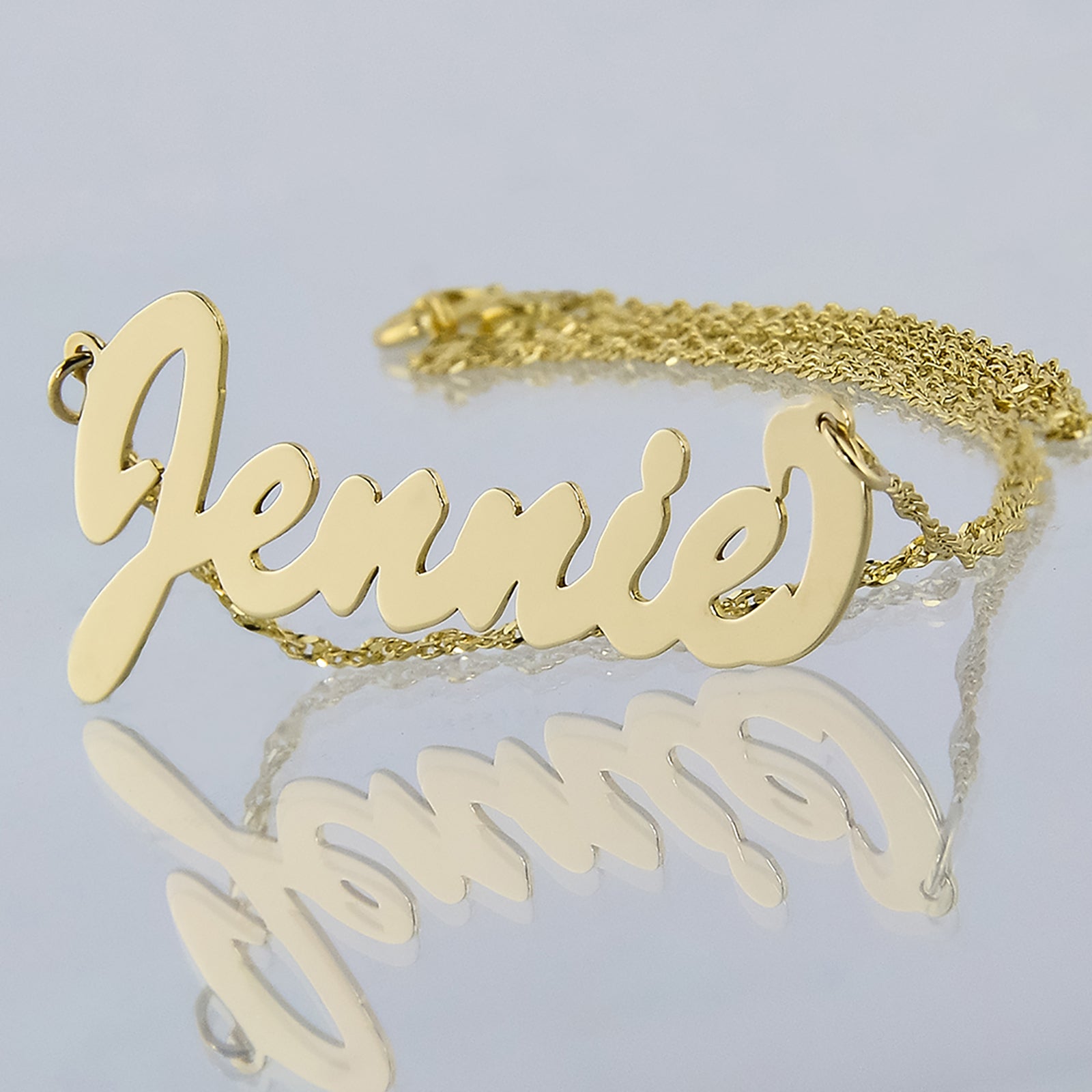Small 10k or 14k yellow gold personalized script nameplate necklace featuring custom cursive lettering for the name Jennie on a gold chain.