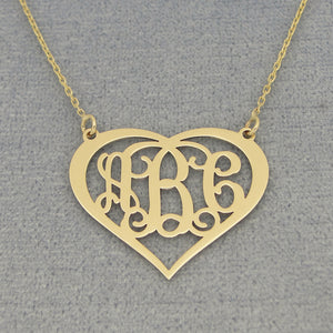Close-up of personalized solid gold heart pendant with three-initial script monogram