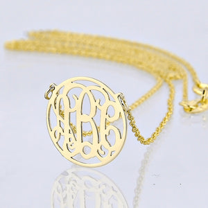 Close-up of a personalized solid gold three-initial circle monogram necklace with reflection.