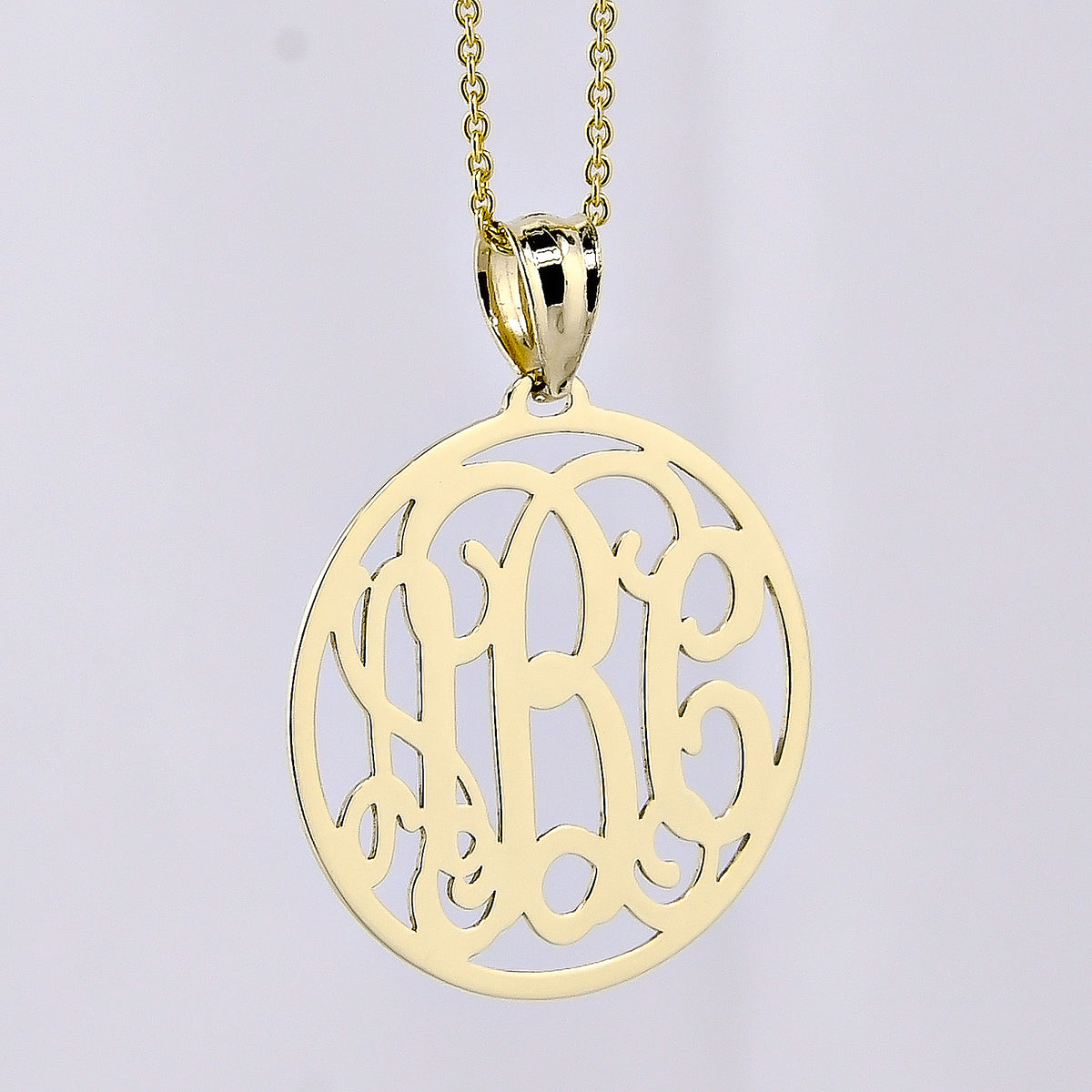 Three-initial solid gold circle monogram pendant necklace on a delicate gold chain.