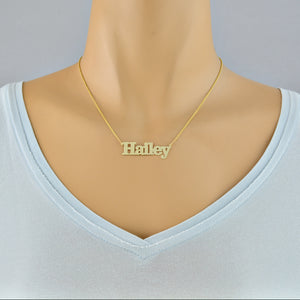 Woman wearing a custom 14k solid gold block font nameplate necklace handcrafted in Los Angeles.