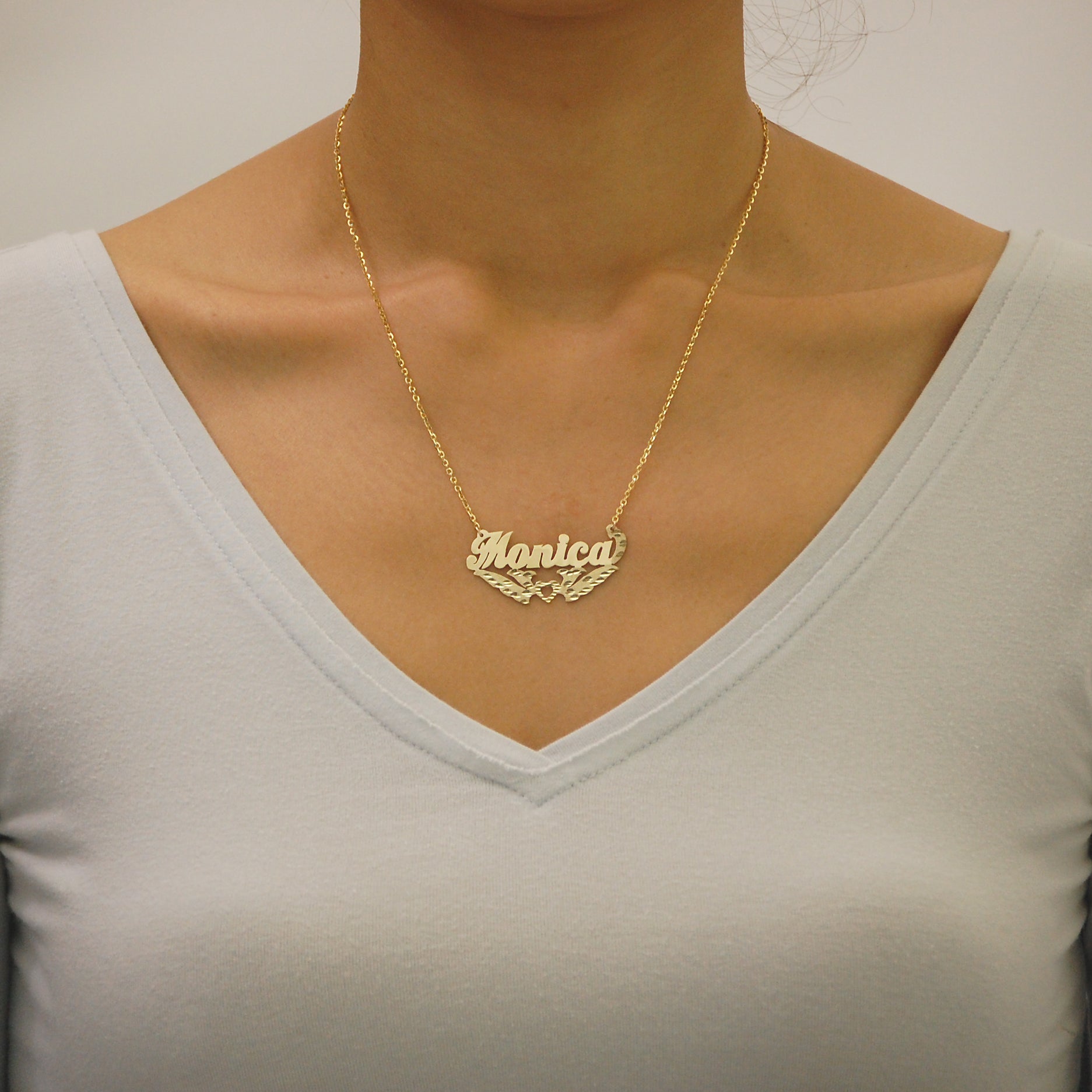 Woman wearing a personalized solid gold diamond-cut nameplate necklace handcrafted in Los Angeles.