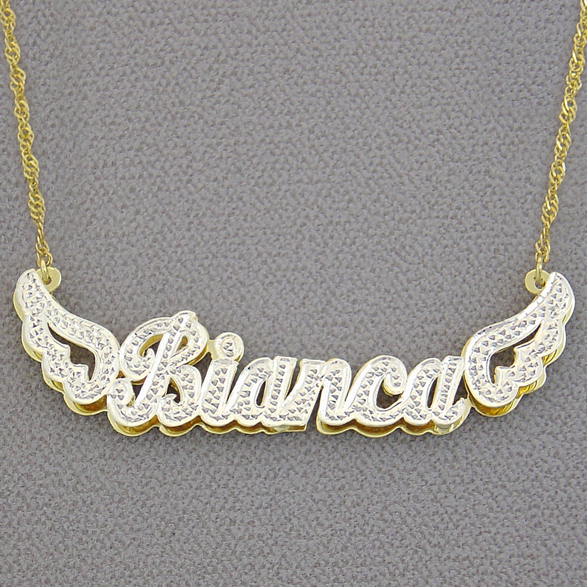 Close-up of the 14k gold hallmark stamp on the back of the custom angel wings name pendant.