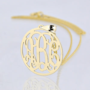A gold monogram pendant with three initials engraved.