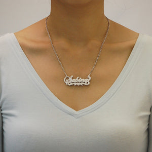 Model wearing a personalized sterling silver 3D cursive nameplate necklace with an 18-inch Rolo chain.