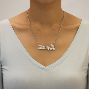 A sterling silver necklace featuring a 3D double skull pendant with the name 'Natasha' personalized on it, in an old English font, with a Rose decoration with 18 inches Rolo chain on a model.