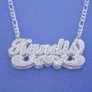 Custom 3D sterling silver cursive name pendant attached to a Figaro chain featuring diamond accents.