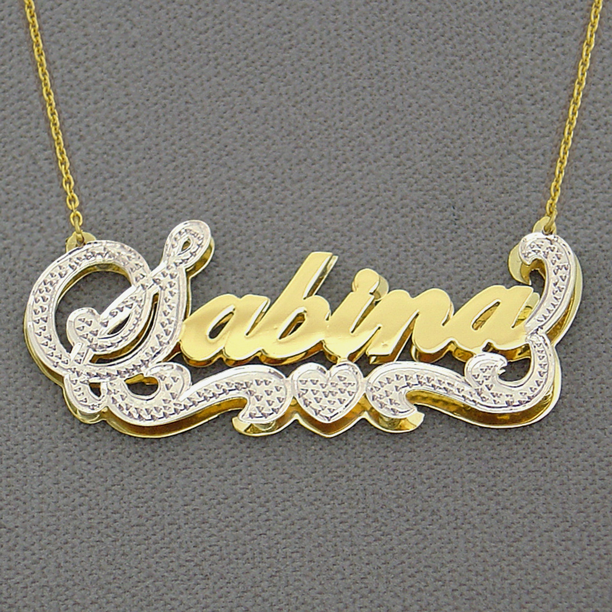 Close-up of custom two-tone 14K gold 3D nameplate displaying hand-carved rhodium diamond-cut accents and cursive text.