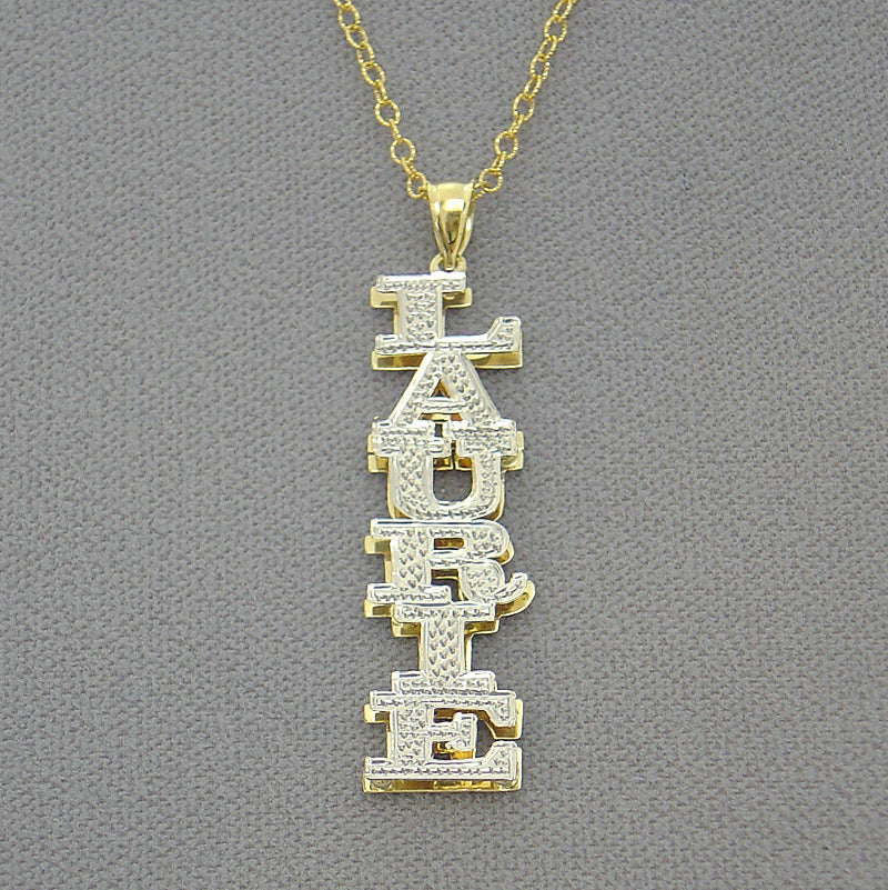Close-up of hand-carved diamond-cut rhodium highlights on vertical gold nameplate.