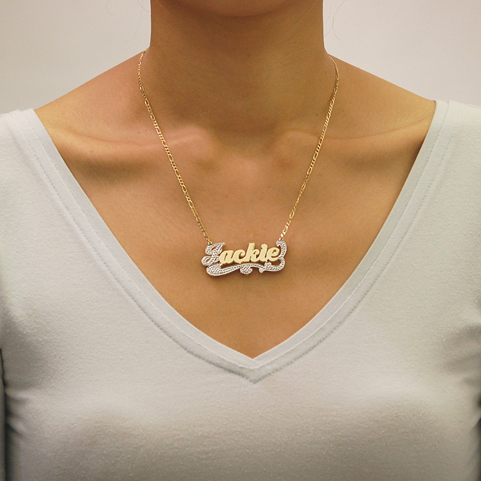 Woman wearing personalized 2-tone 3D gold nameplate necklace with Figaro chain.