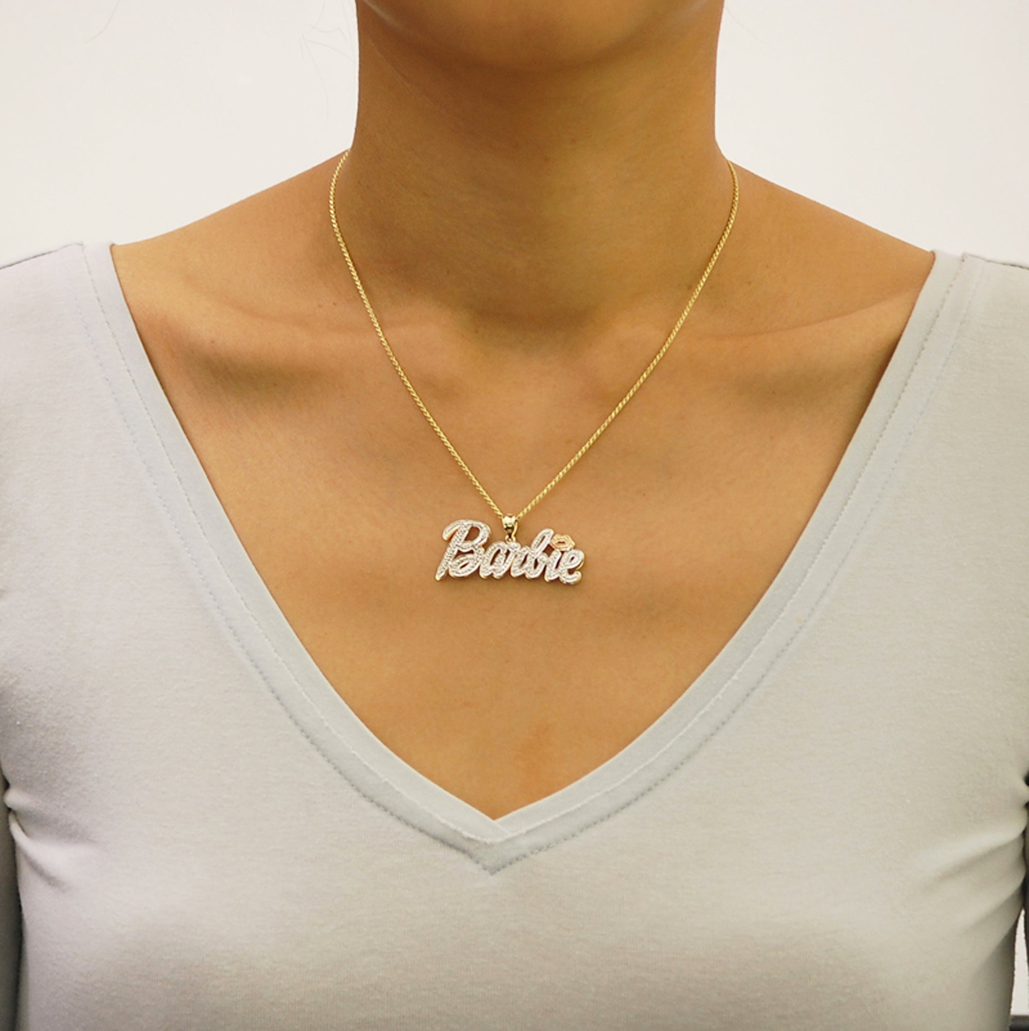 Model wearing a 10k solid gold 3D Barbie nameplate necklace with diamond accents.