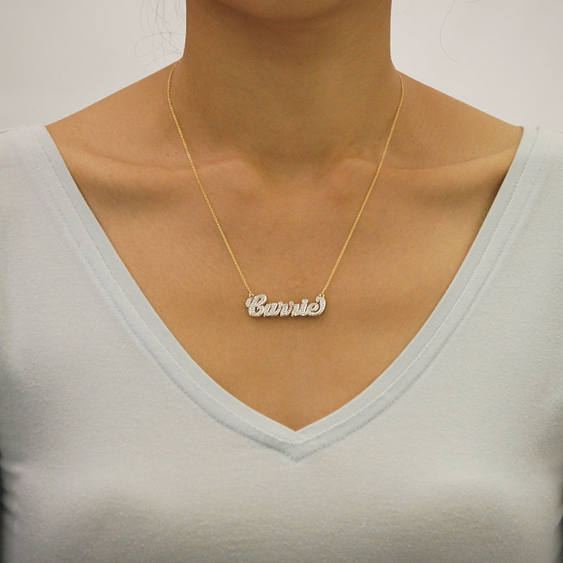 Model wearing a 1.5-inch custom solid gold 3D double plate name pendant on a gold chain.