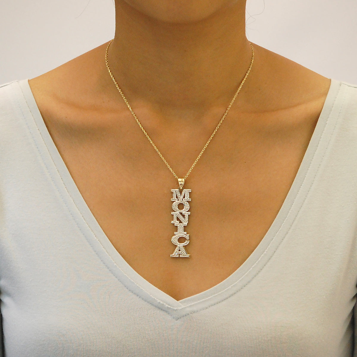Model wearing 10K solid gold large vertical 3D name necklace with diamond accents